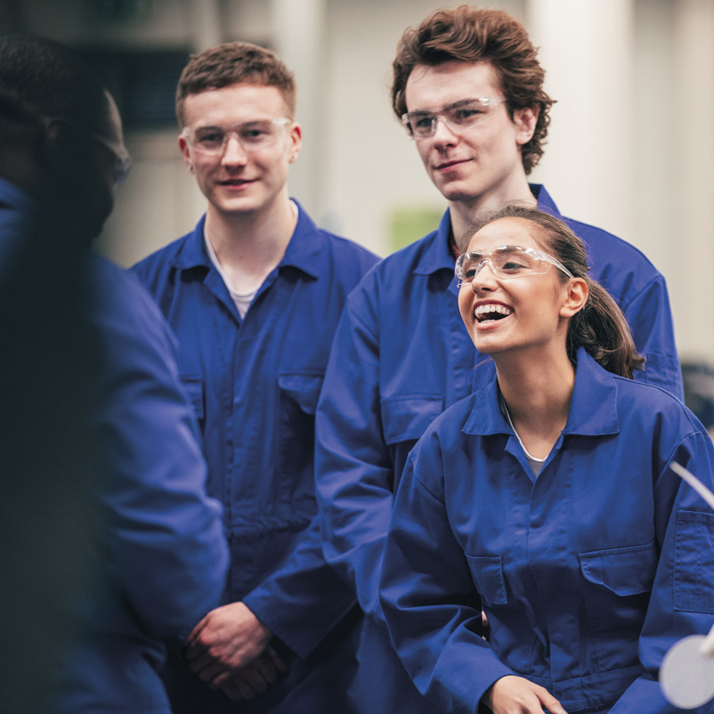 group of young employees in boiler suits laughing and smiling
